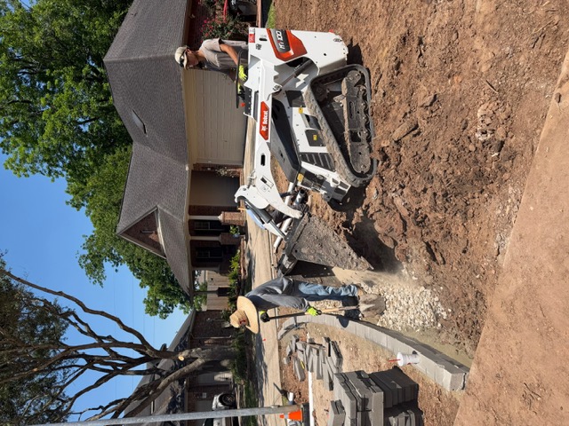 Compact track loader excavating a residential drainage trench