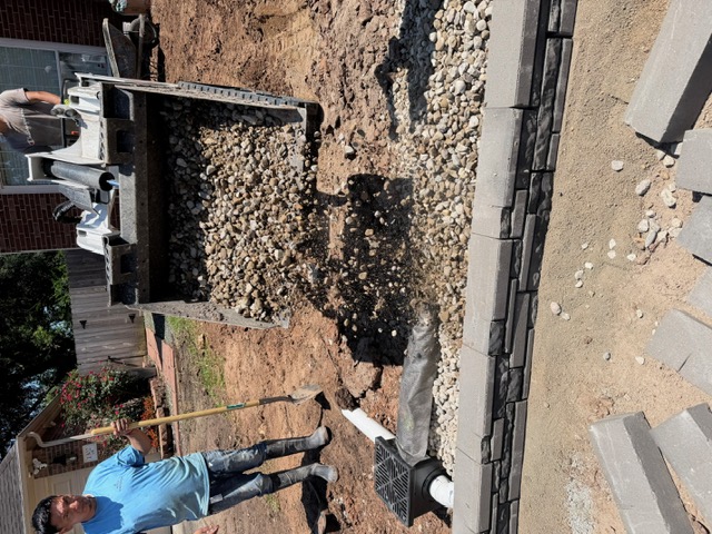 Drainage inlet and stone base beside a retaining wall
