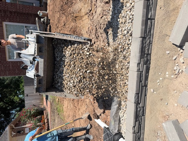 Compact loader placing drainage aggregate on a residential project