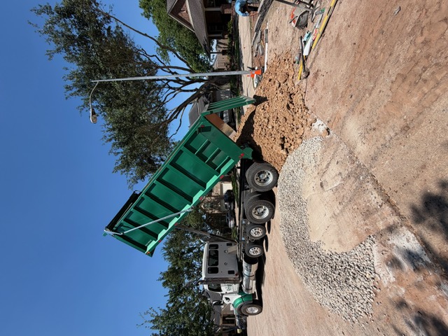 Dump truck delivering bulk material to a residential site
